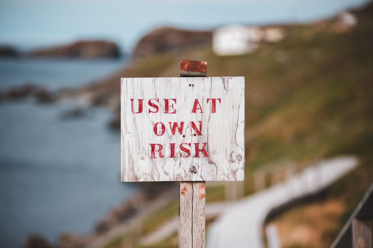 cliff پر Use At Own Risk کا بورڈ — اوپن کاغذات پر چلنے کا خطرہ