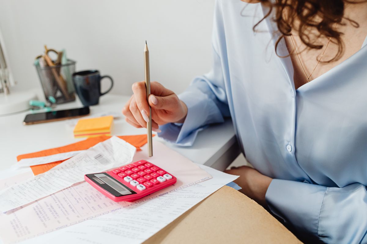 کیلکولیٹر اور کاغذات سے حساب کرتی خاتون — وراثتی انتقال کی فیس و دورانیہ